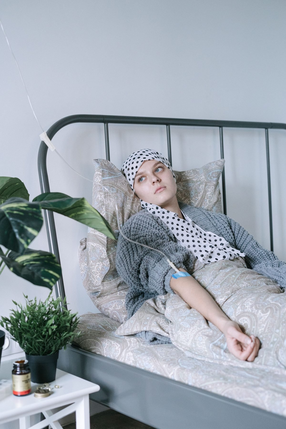 A young breast cancer patient in a headscarf, resting during treatment with an IV line